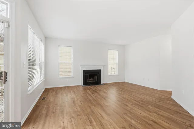 a view of empty room with wooden floor and fireplace