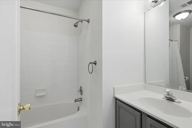 a bathroom with a tub sink vanity granite and shower