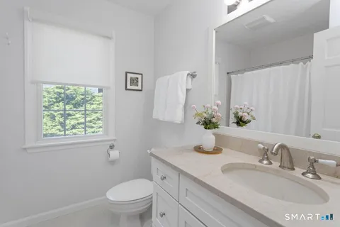 a bathroom with a granite countertop toilet a sink and a mirror