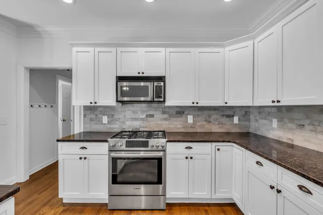 a kitchen with granite countertop white cabinets and stainless steel appliances