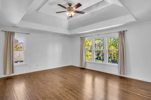 a view of an empty room with a window and wooden floor