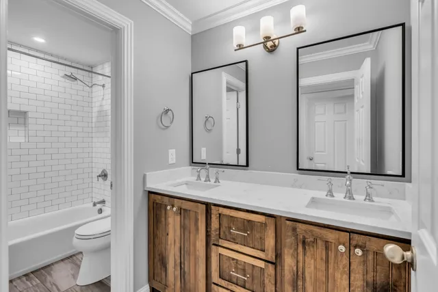 a bathroom with a granite countertop sink a toilet a mirror a bathtub and shower