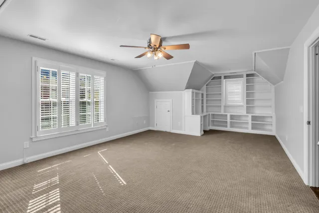 an empty room with windows and ceiling fan