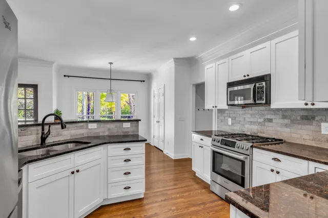 a kitchen with granite countertop white cabinets and stainless steel appliances