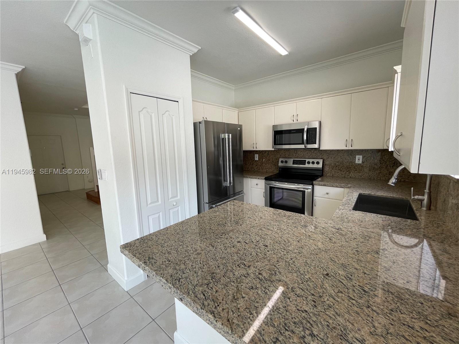 7020 Northwest 177th Street, Unit B103 Hialeah, FL 33015 - Photo 12 of 53 a kitchen with granite countertop a refrigerator and a sink