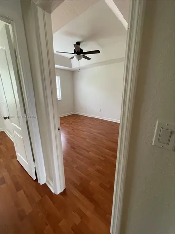 a view of empty room with wooden floor and ceiling fan