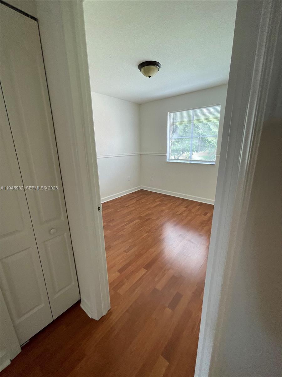 7020 Northwest 177th Street, Unit B103 Hialeah, FL 33015 - Photo 21 of 53 an empty room with wooden floor and windows