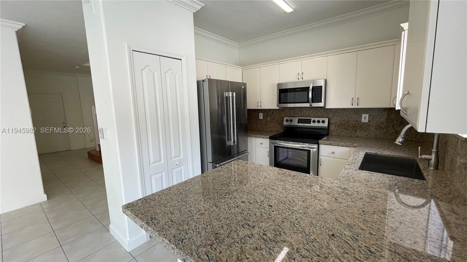 7020 Northwest 177th Street, Unit B103 Hialeah, FL 33015 - Photo 40 of 53 a kitchen with granite countertop a refrigerator sink and stove