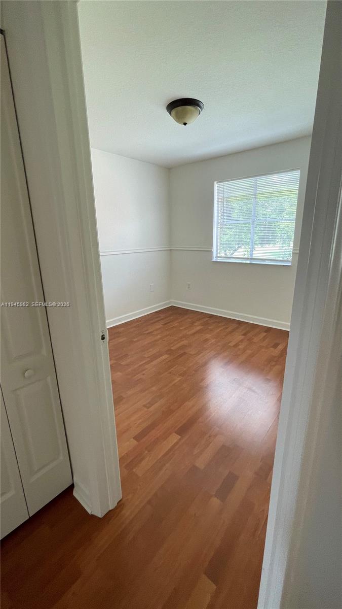 7020 Northwest 177th Street, Unit B103 Hialeah, FL 33015 - Photo 48 of 53 an empty room with wooden floor and windows