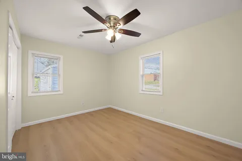 an empty room with a chandelier fan and windows