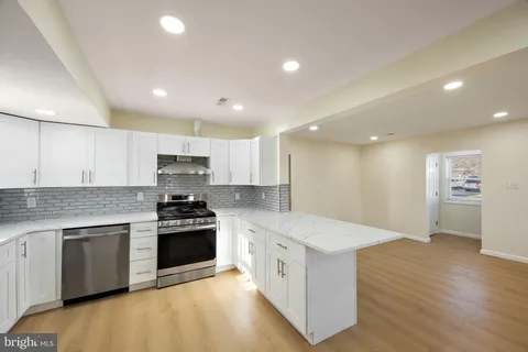 a kitchen with stainless steel appliances white cabinets a sink a stove a refrigerator and a microwave