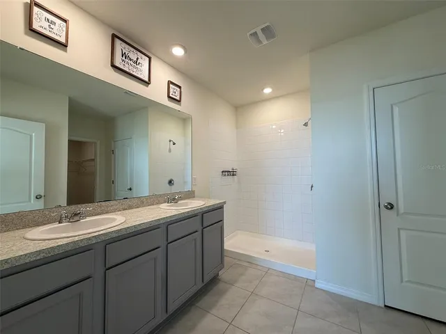a spacious bathroom with a granite countertop sink a mirror and a bathtub
