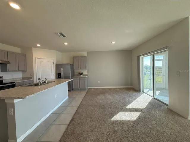 a large hall with stainless steel appliances granite countertop a large counter top a stove and a refrigerator