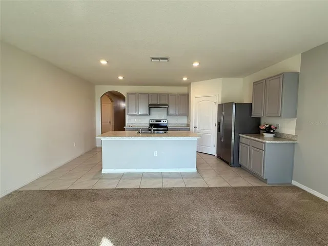 a large kitchen with kitchen island a refrigerator a sink dishwasher a stove with white cabinets and a refrigerator