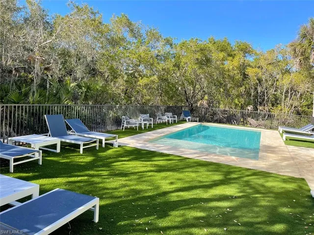 a view of a swimming pool with lawn chairs and a yard