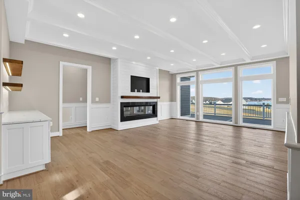a view of an empty room with wooden floor and a fireplace