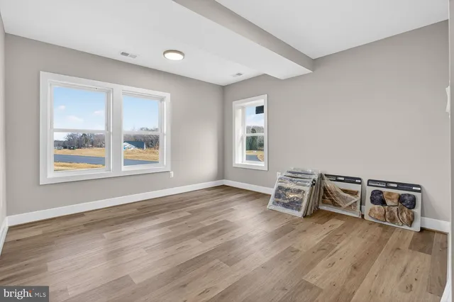 a view of an empty room with wooden floor and a large window