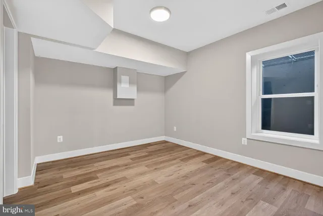 a view of an empty room with wooden floor and kitchen