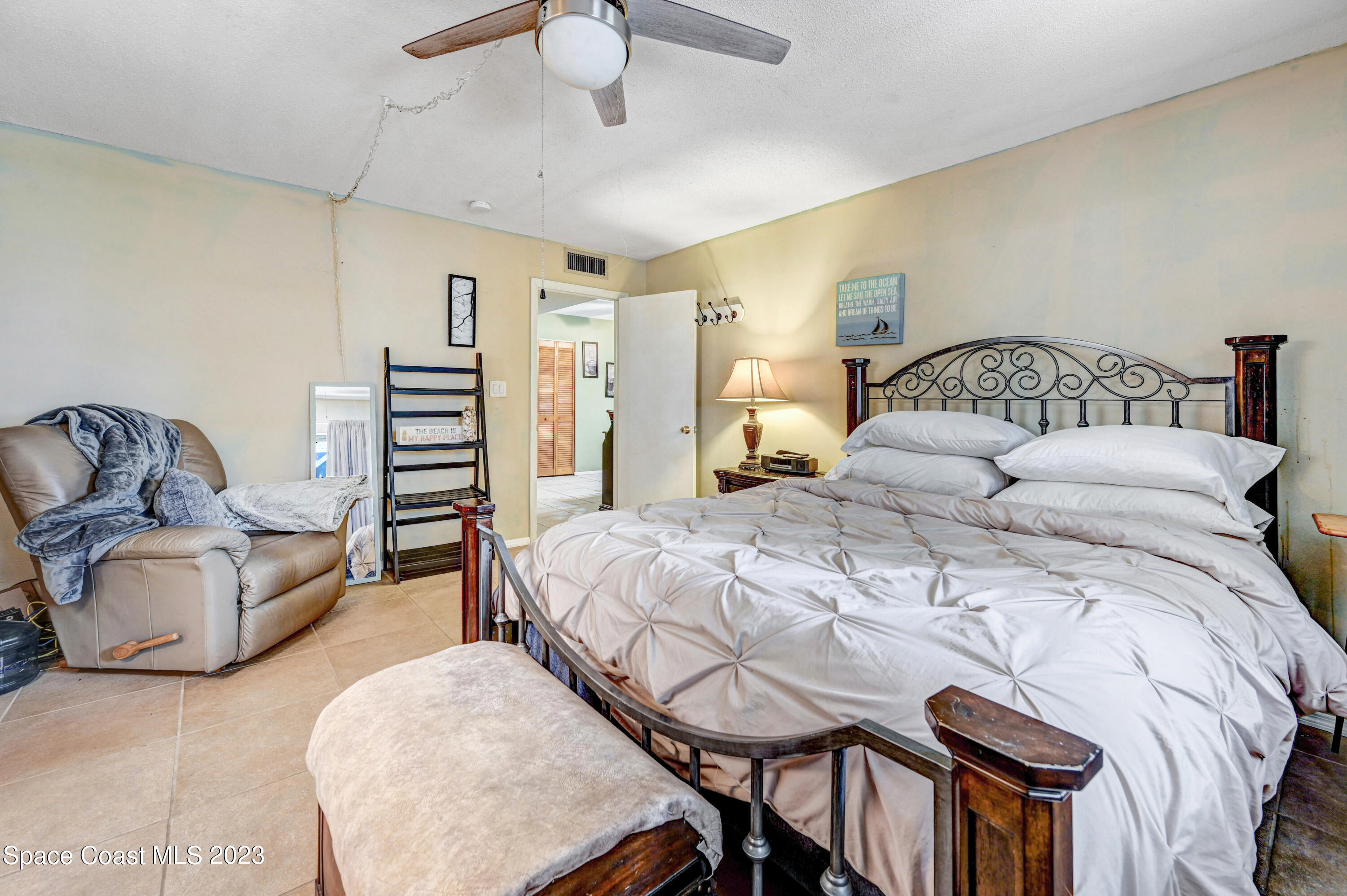 832 Damask Street Northeast Palm Bay, FL 32905 - Photo 10 of 18 a bedroom with a bed couch and a chandelier