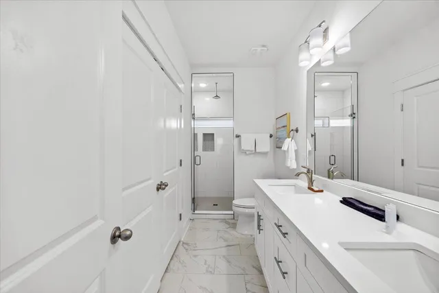 a spacious bathroom with a double vanity sink a mirror and a shower