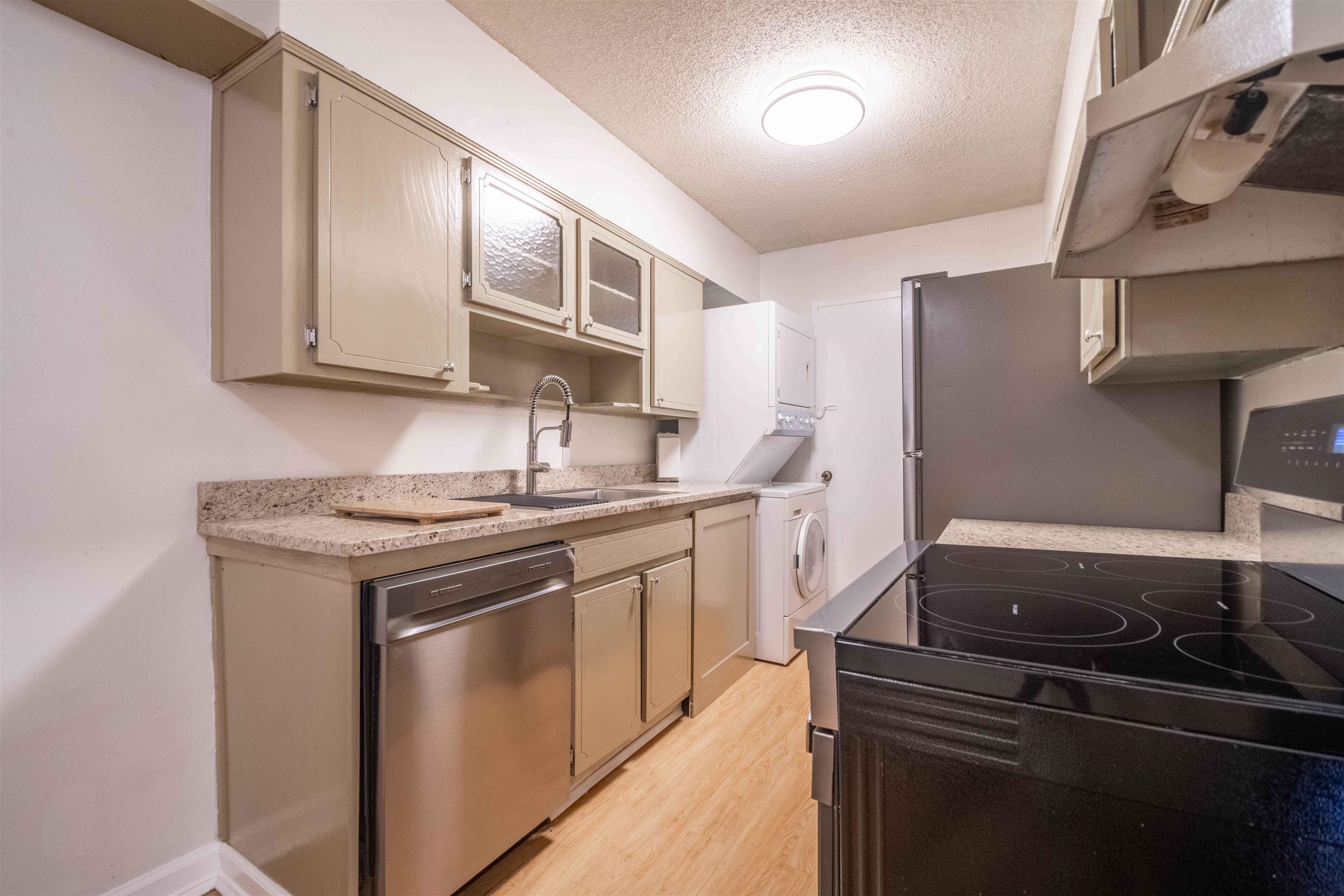 3080 Walnut Grove Road, Unit 306 Memphis, TN 38111 - Photo 8 of 18 Kitchen featuring light-toned cabinetry, granite-finish countertops, stainless steel dishwasher, and a black flat-top electric range