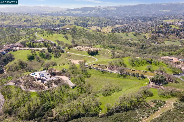 an aerial view of residential houses with outdoor space and trees