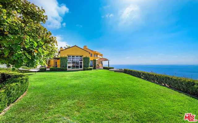 a view of a big house with a big yard and potted plants in front of a house