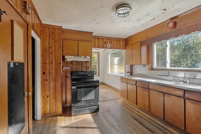 a kitchen with stainless steel appliances granite countertop a refrigerator a sink dishwasher a stove and a dining table with wooden floor