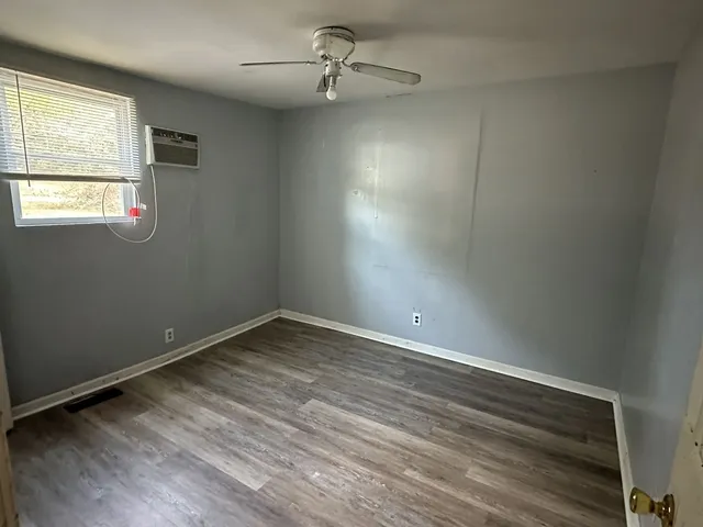 an empty room with a window and ceiling fan