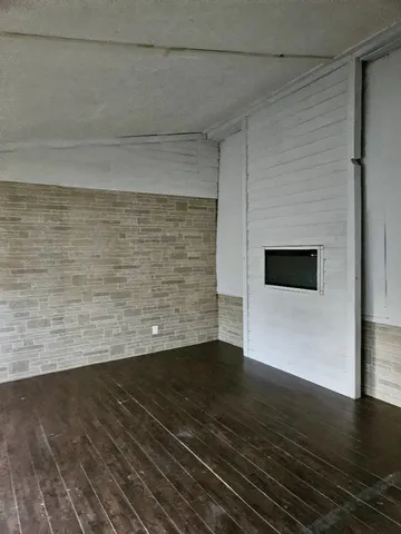 a view of an empty room with wooden floor and a fireplace