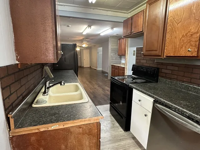 a kitchen with kitchen island granite countertop a sink a stove and a wooden cabinets