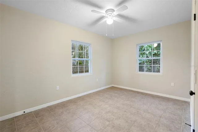 an empty room with windows and fan