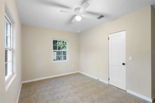 an empty room with a window and a fan