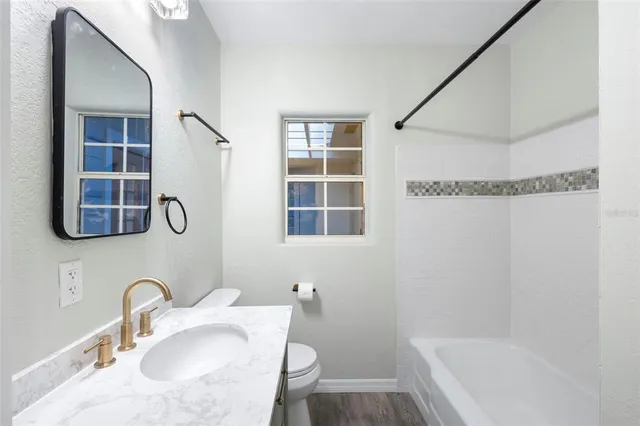 a bathroom with a granite countertop sink a mirror and a bathtub