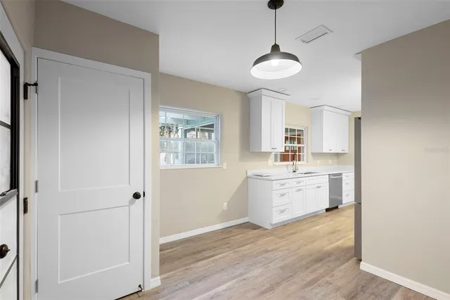 a kitchen with cabinets wooden floor and a window