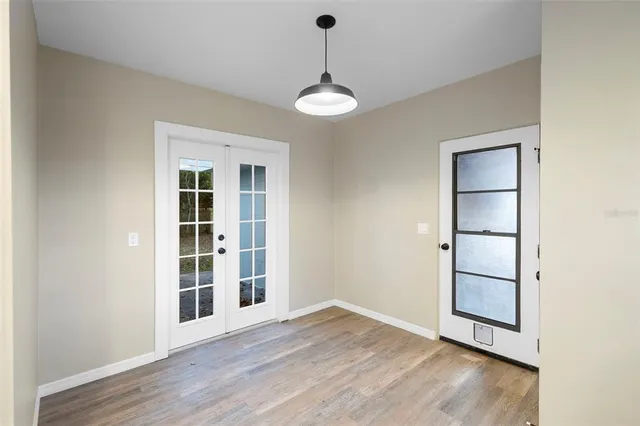 an empty room with wooden floor cabinet and windows