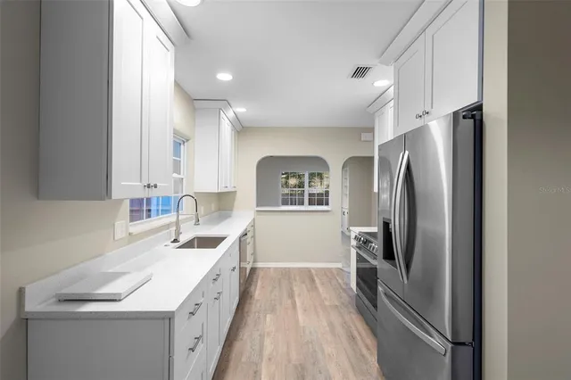 a kitchen with a sink a counter top space stainless steel appliances and cabinets