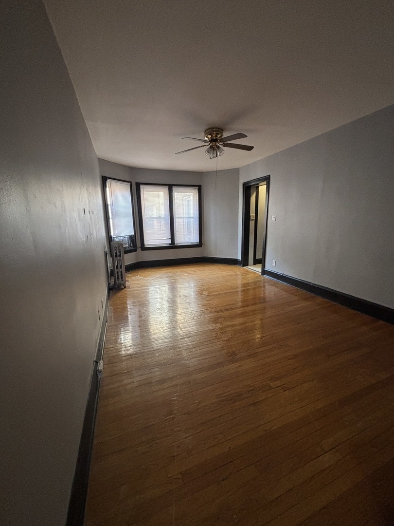 2212 East 70th Street, Unit 2D Chicago, IL 60649 - Photo 2 of 8 an empty room with wooden floor and windows