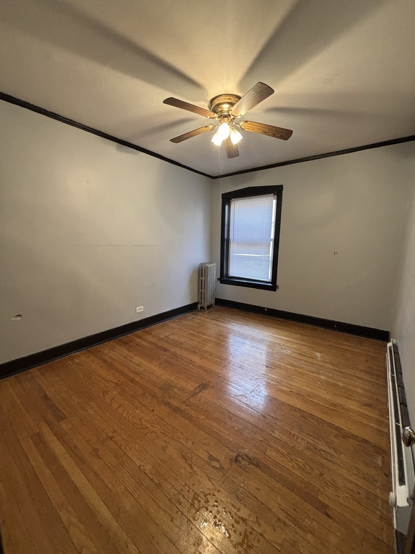 2212 East 70th Street, Unit 2D Chicago, IL 60649 - Photo 6 of 8 an empty room with a window and wooden floor