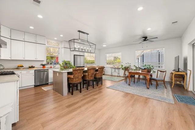 a open kitchen with lots of furniture a sink appliances and a dining table