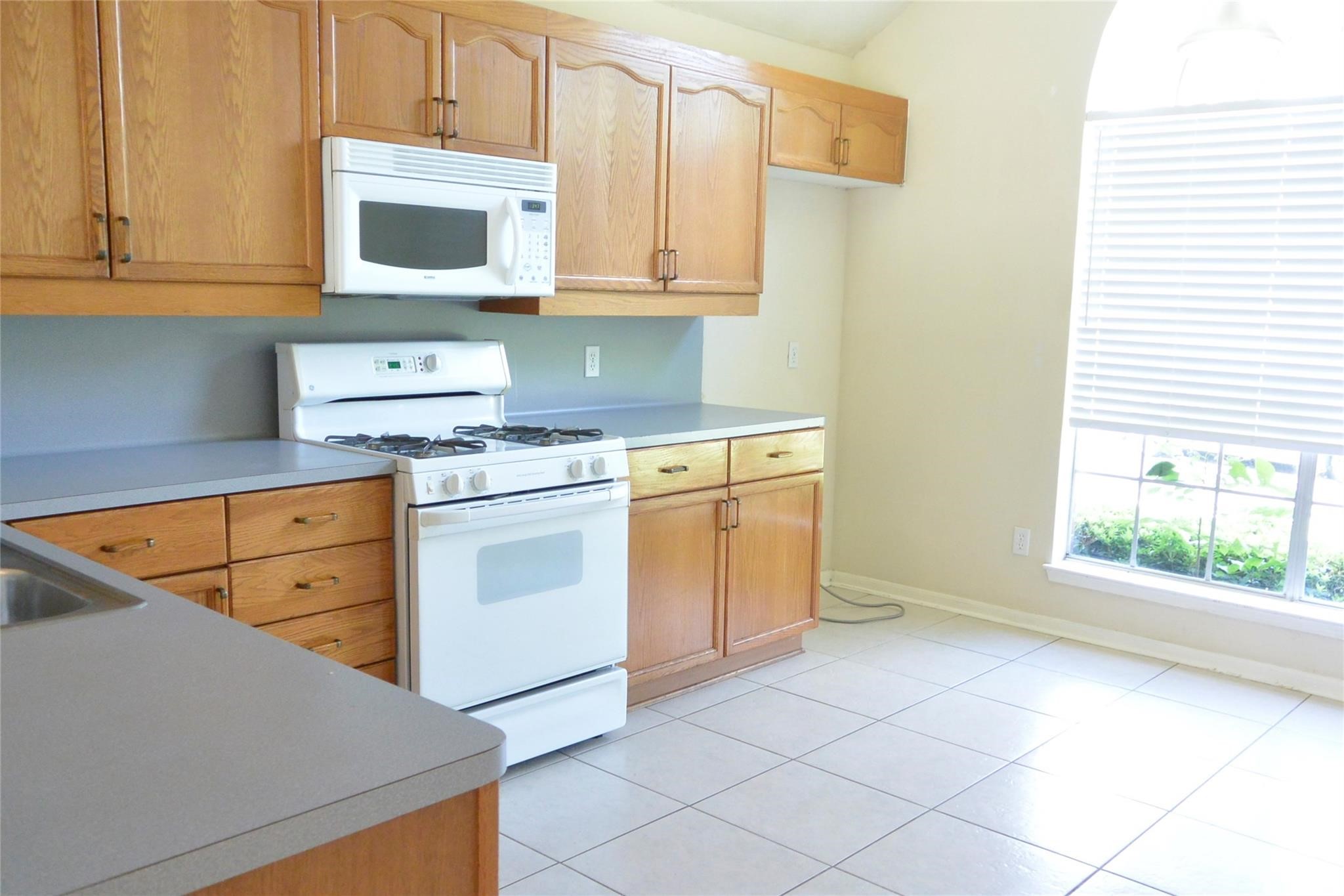 23615 Tree House Lane Spring, TX 77373 - Photo 2 of 12 a kitchen with stainless steel appliances granite countertop a stove a sink and a microwave