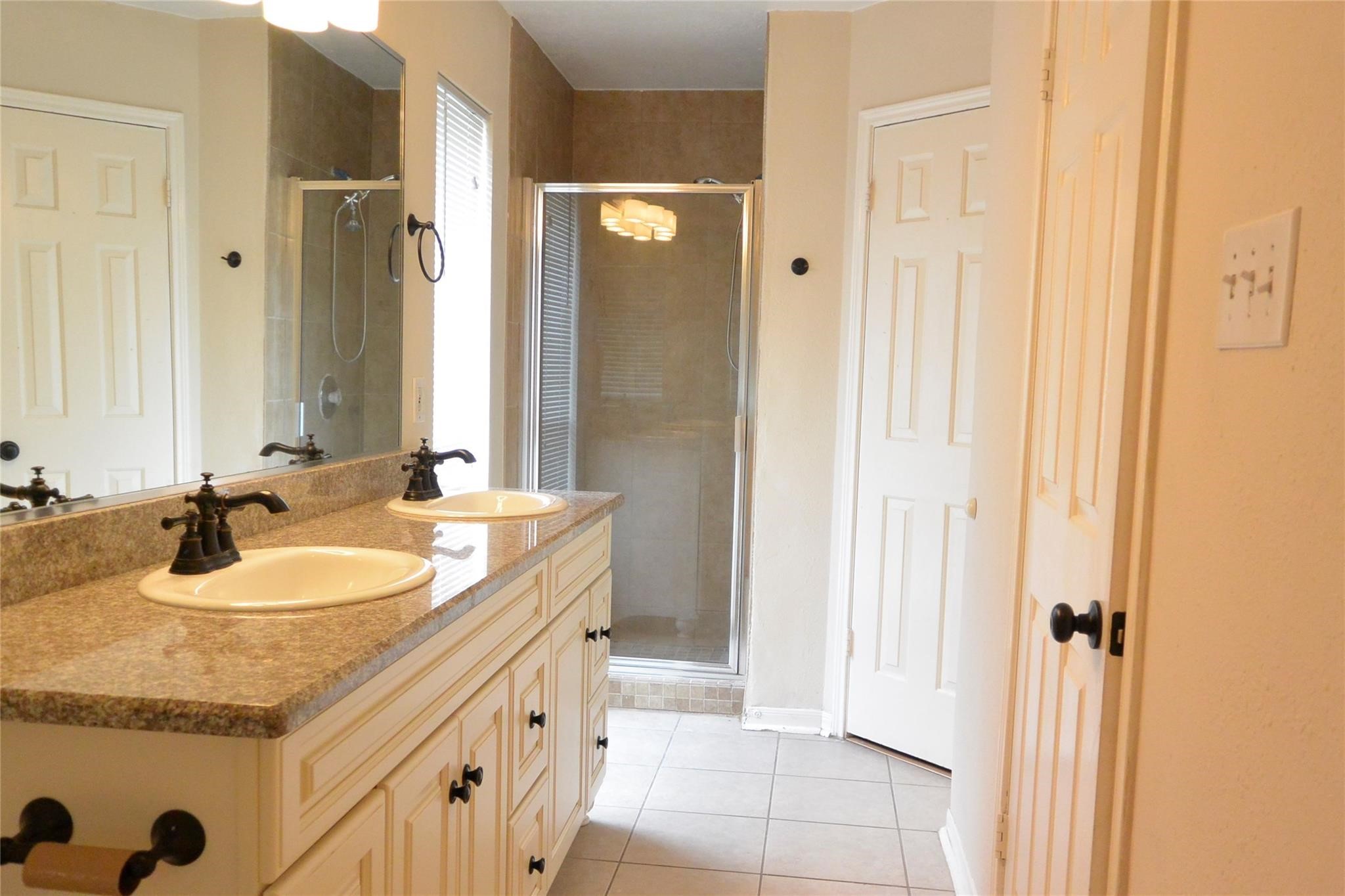 23615 Tree House Lane Spring, TX 77373 - Photo 6 of 12 a bathroom with a double vanity sink a mirror and a bathtub