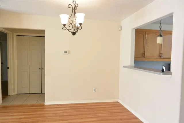 a view of a hallway with wooden floor and chandelier