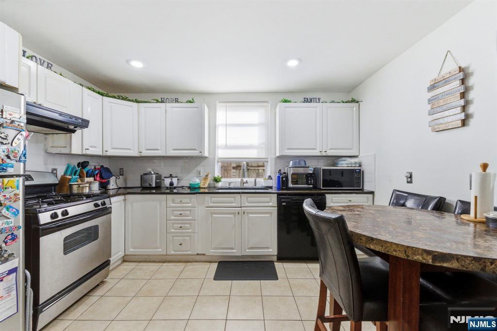270 Westervelt Place Lodi, NJ 07644 - Photo 6 of 17 a kitchen with a stove a sink and white cabinets