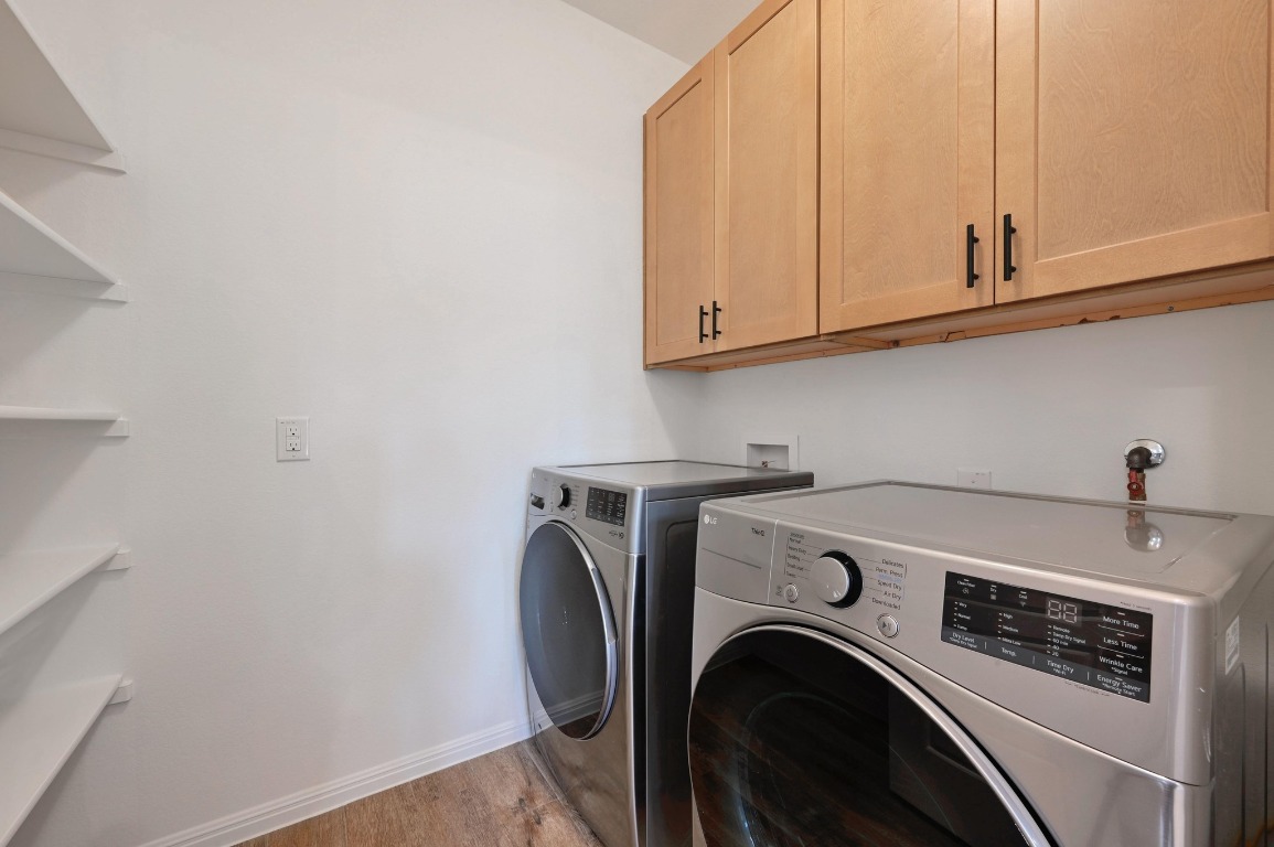 13221 Mariscan Street Manchaca, TX 78652 - Photo 15 of 36 Laundry area with light wood finished floors, cabinet space, and washer and dryer