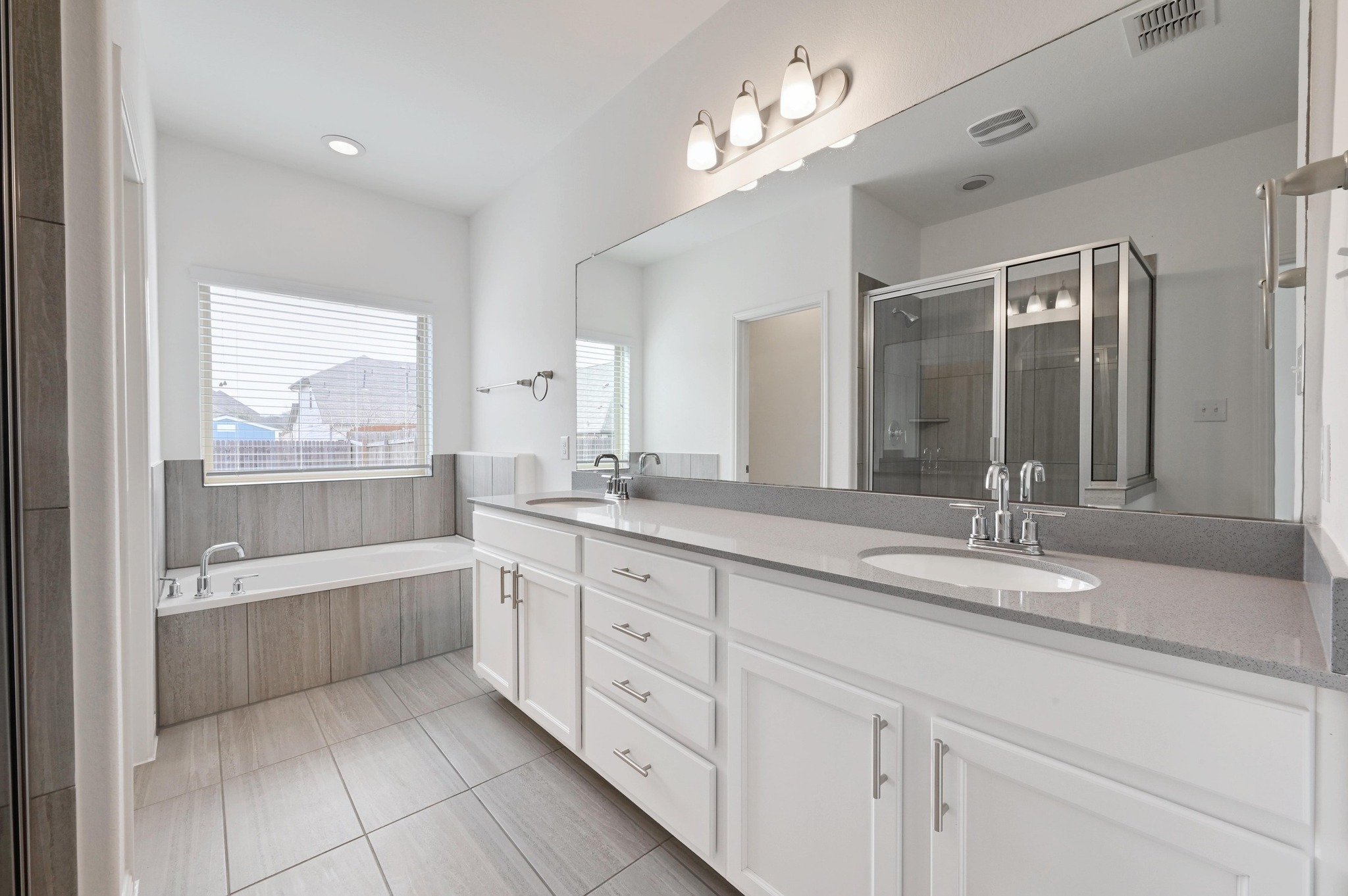 13221 Mariscan Street Manchaca, TX 78652 - Photo 18 of 36 a bathroom with a granite countertop bathtub a double vanity sink a vanity a window and a mirror