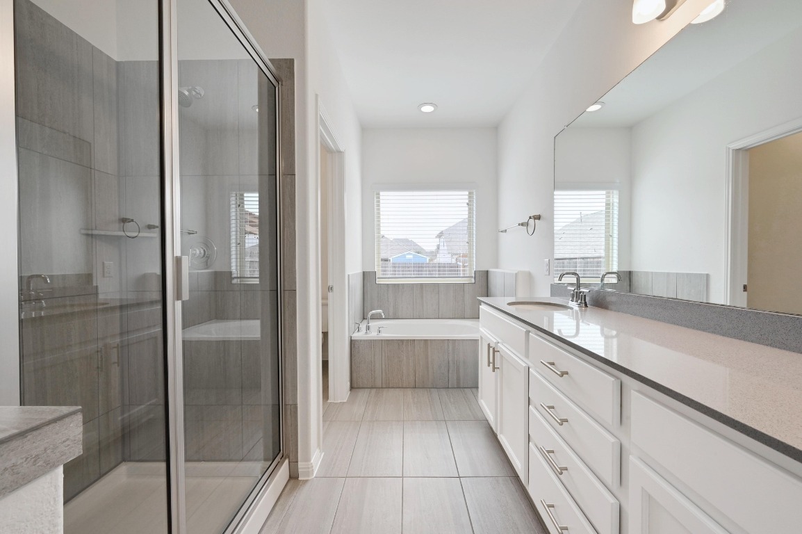 13221 Mariscan Street Manchaca, TX 78652 - Photo 19 of 36 Full bath with a stall shower, vanity, a garden tub, and light tile patterned flooring