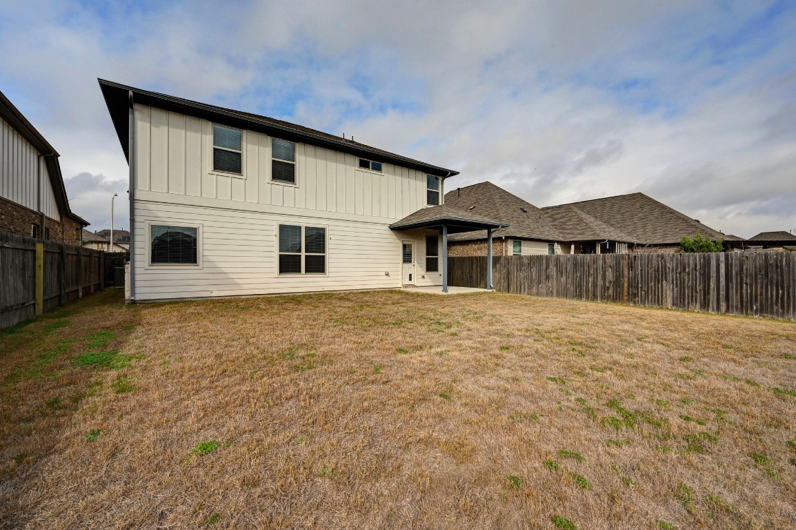 13221 Mariscan Street Manchaca, TX 78652 - Photo 31 of 36 Rear view of house with a patio area, a fenced backyard, and board and batten siding