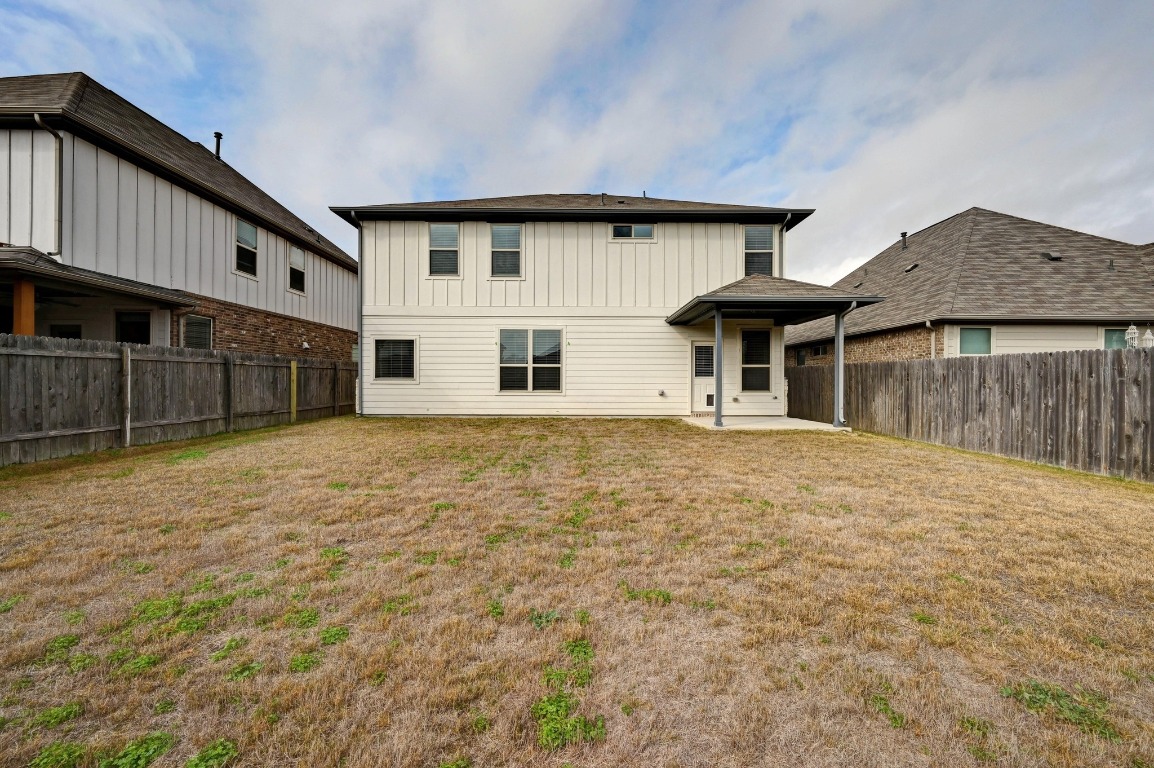 13221 Mariscan Street Manchaca, TX 78652 - Photo 32 of 36 Rear view of house with a patio, a fenced backyard, and board and batten siding