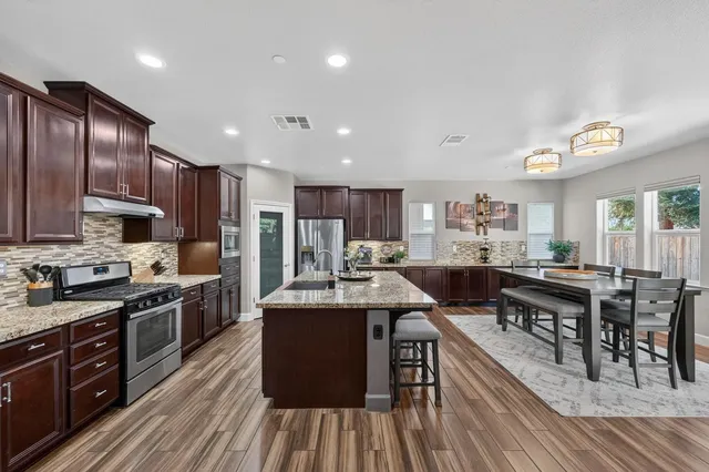 a kitchen with stainless steel appliances granite countertop wooden cabinets a stove a sink and a refrigerator
